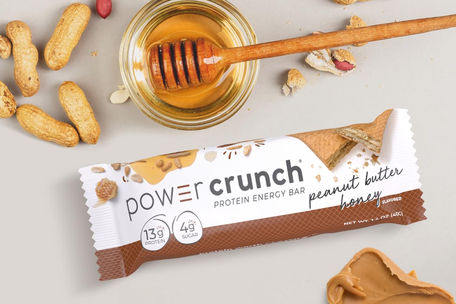 Power Crunch Peanut Butter Honey bar next to bowl of honey and peanuts and peanut butter